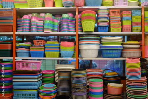 Plastic containers and colorful household items on store shelves. Kitchen plastic bowls, storage boxes, and baskets in a retail display.
