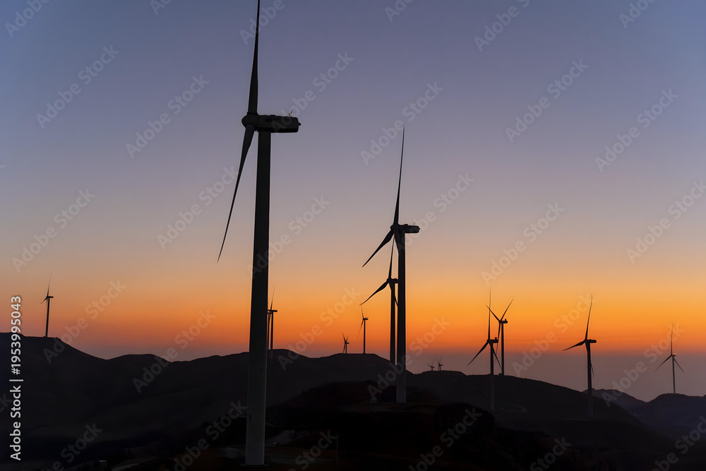 Obraz premium Wind Turbines Silhouetted Against Golden Sunset Sky