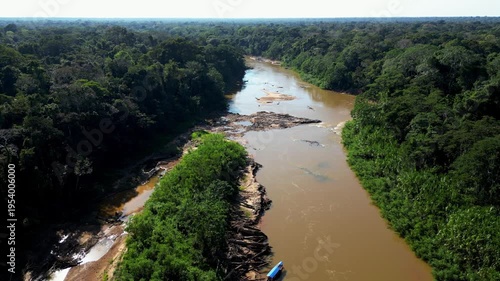 Cinematic aerial drone footage of a winding river flowing through dense Amazon rainforest in Tambopata. The tropical jungle surrounds the riverbanks while sandbars shape the water flow