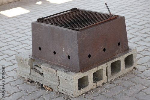Tableau sur toile crude makeshift grill on paving stones using concrete building blocks, rusty iro