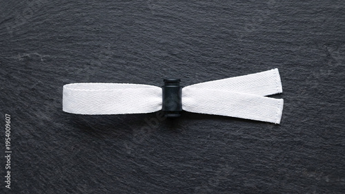 Blank white fabric wristband mockup with black plastic lock on dark stone