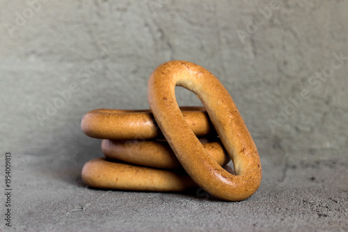 A stack of delicious, golden-brown pretzels lies against a gray background. One of them leans against the others at an angle, creating a three-dimensional composition. Minimalism and comfort.
