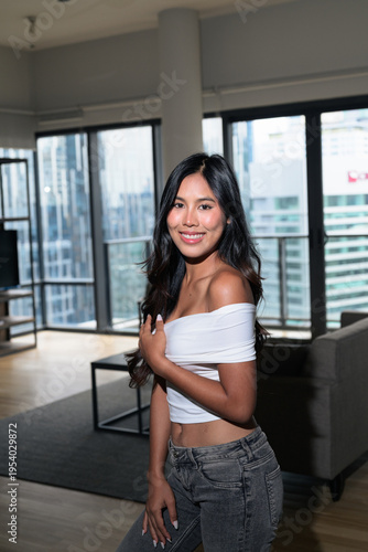Young Asian woman standing in a modern high-rise apartment with city view in Kuala Lumpur, Malaysia Free Download Young Asian woman standing in a modern high-rise apartment with city view in Kuala Lumpur, Malaysia - GFXLoad