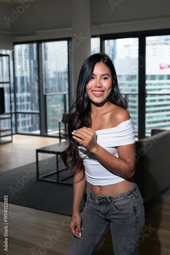 Photography Young Asian woman standing in a modern high-rise apartment with city view in Kua