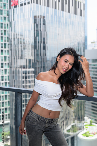 Young Asian woman posing on a high-rise balcony with modern skyscrapers in Kuala Lumpur, Malaysia