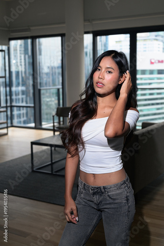 Photography Young Asian woman standing in a modern high-rise apartment with city view in Kua