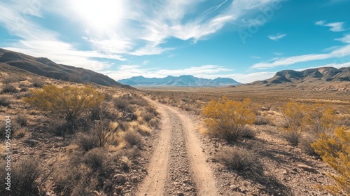 Expansive desert landscape with a dusty offroad trail leading towards distant mountains under a bright, cloud-filled sky