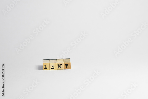 Lent word spelled thru wooden blocks in a white background. Simple design.