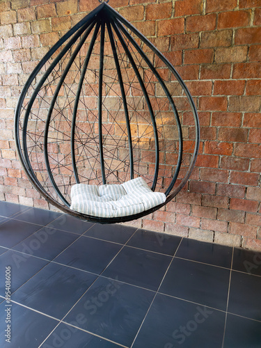 Modern Hanging Metal Egg Chair Against Rustic Brick Wall.