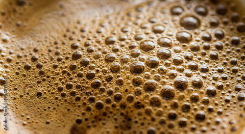 Extreme macro close-up of rich, dark brown liquid with dense foam bubbles, resembling freshly brewed coffee or espresso crema. Highly detailed texture with varying bubble sizes.