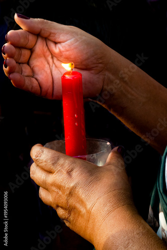 Принти на полотні A woman's hand protects the flame of a red candle, firmly held by another hand