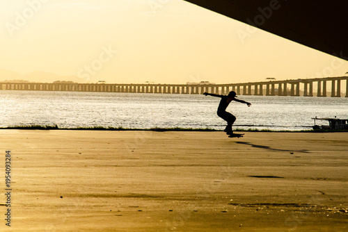 Backlit image of a skateboarder at dusk performing a trick near a lagoon. The scene evokes skateboarding culture as a contemporary expression in dialogue with the landscape of Rio de Janeiro.