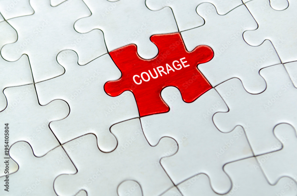 Fototapeta premium COURAGE, Single red courage puzzle piece positioned alone in the center of a white interlocking jigsaw puzzle surface