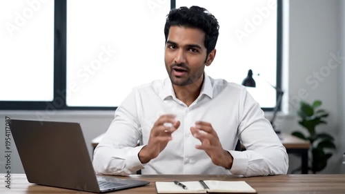 Businessman talking and gesturing in office with laptop and notebook