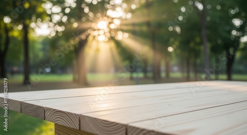 A close up of a light wooden picnic table surface in a park with sunset rays through the trees