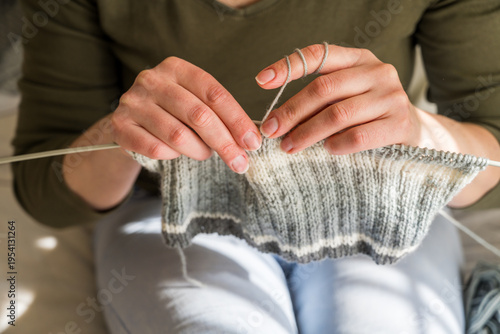Fotografie Woman knitting, close-up hands with yarn and knitted scarf
