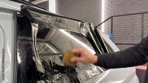Technician Installing car window tint. Window toned film. Car window tinting specialist install car film windscreen. Applying tinting foil on a window in the detailing studio. Concept of love cars. 