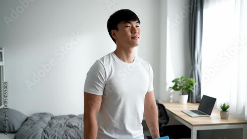 Young man drinks water in a bright home office setting.