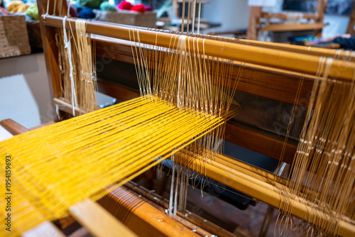 Close up of traditional textile weaving loom with golden yarn