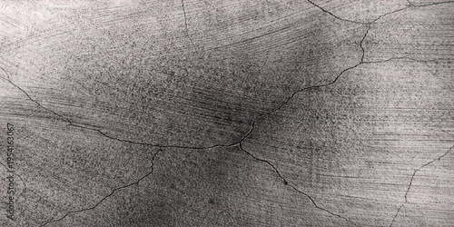 A close up view of a weathered grey concrete wall surface featuring deep structural crack lines