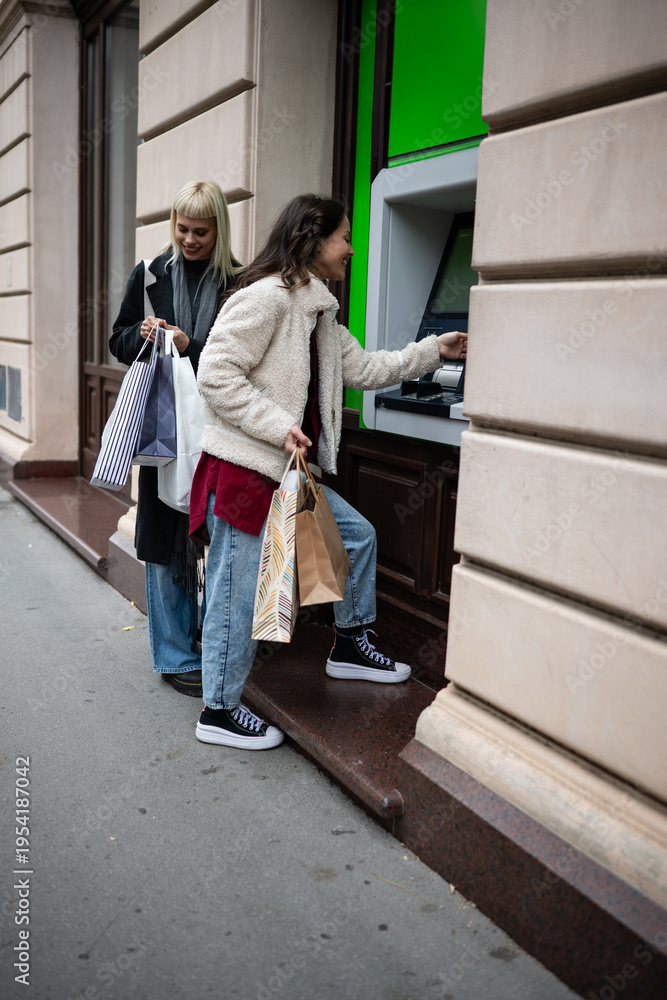 Fototapeta premium Women shopping, withdrawing money from atm cash machine