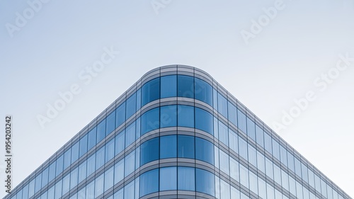 A modern glass office building with a clear blue sky background