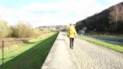 Beautiful girl in a yellow jacket walks along a pedestrian path in Kazimierz Dolny, Poland.