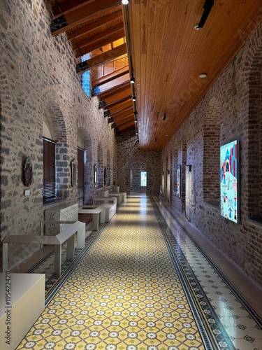 An atmospheric interior of a historic bathhouse featuring stone architecture, traditional bathing basins, and decorative patterned tiles. The combination of textured stone walls, warm wooden elements,