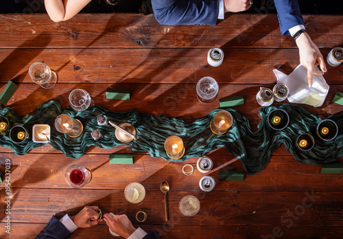 High angle view of people having a dinner party with drinks and food in a formal setting, hands indicate people having conversation.