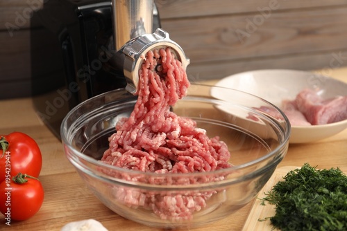 Konstfotografi Electric meat grinder with minced meat and ingredients on wooden table in kitche