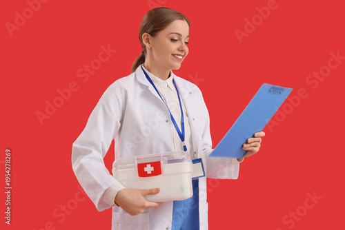 Female doctor with first aid kit and clipboard on red background