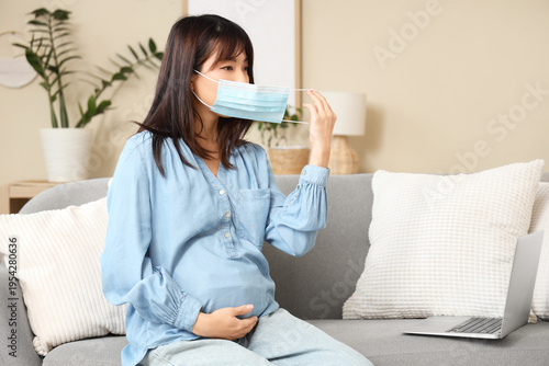 Pregnant Asian woman puttin...