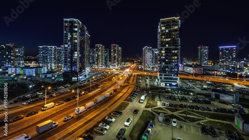 night time lapse with light in windows of multistory skyscraper buildings and avenue and lights from car headlights. life in a big city. Serenade of light