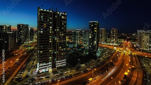 night time lapse with light in windows of multistory skyscraper buildings and avenue and lights from car headlights. life in a big city. Serenade of light