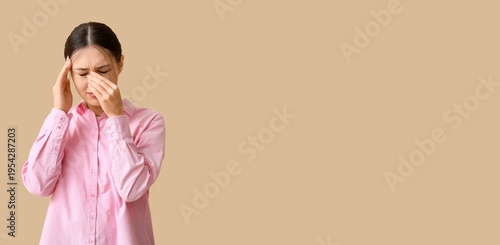 Young Asian woman suffering from headache on beige background with space for ...