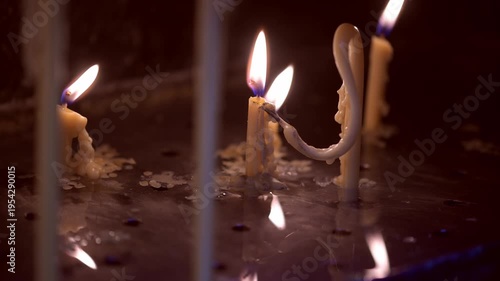 A candle burns softly, casting warm light through the gap of heavy metal doors