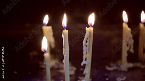 A candle burns softly, casting warm light through the gap of heavy metal doors