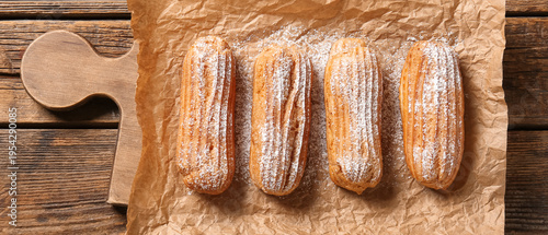 Board with tasty eclairs on...