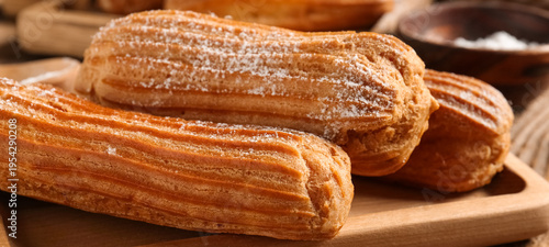 Board with tasty eclairs on...