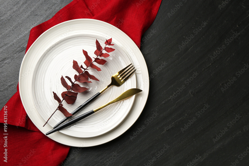 Obraz premium Stylish setting with cutlery, napkin and branch on black table, top view