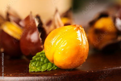 Fresh Roasted Chestnuts with Golden Shells and Mint Garnish on Wooden Surface