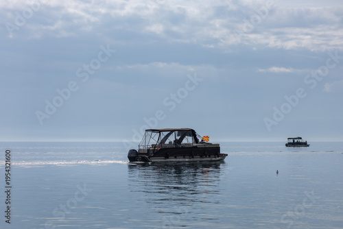 Foto pontoon boat with macedonian flag cruising on calm blue lake water under a cloud