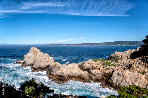 Blue sky meets crashing waves against jagged rocks