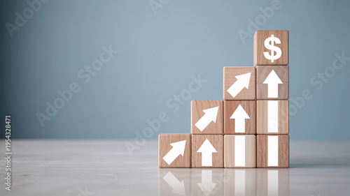 A stack of wooden blocks with arrows and a dollar sign, symbolizing financial growth and success.