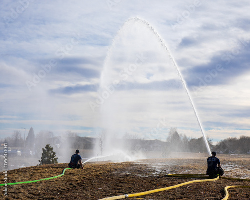 Canvas Print Firefighters from ladder company number 5 train on focusing the fire hose spray onto a target in a local neighborhood