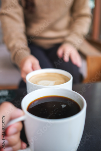 Vertical closeup image of couple people clinking coffee cups in cafe