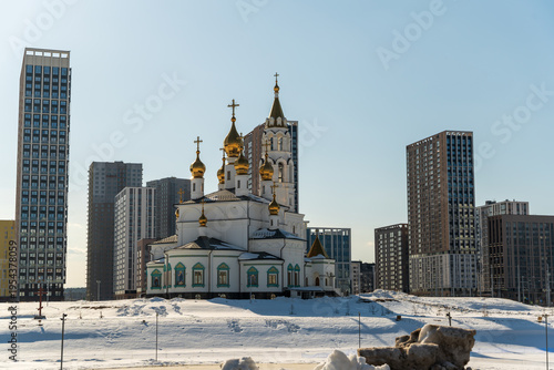 Wallpaper Mural Yekaterinburg, Russia - March 18, 2026: A bright, clear spring day with an Orthodox church featuring golden onion domes, surrounded by modern high-rise buildings and snow-covered ground. Torontodigital.ca