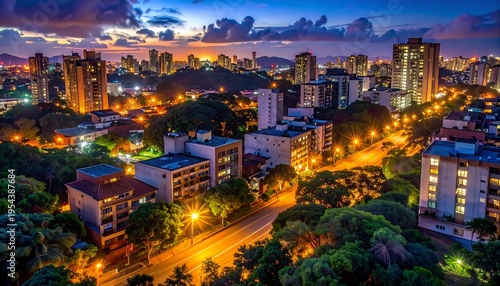 Wallpaper Mural Aerial view of a city at dusk, showcasing illuminated buildings, roads, and lush green trees beneath a colorful sky Torontodigital.ca