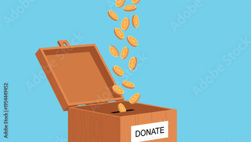 Gold coins falling into a wooden charity donation box with a white label against a clear blue background representing philanthropy.