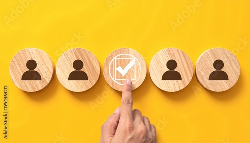 Hand selecting marked token among wooden people icons